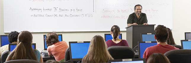 Rear view of a group of students sitting in front of computer monitors